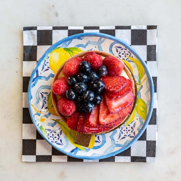A vibrant fruit tart with strawberries, blueberries, and raspberries on a decorative plate.